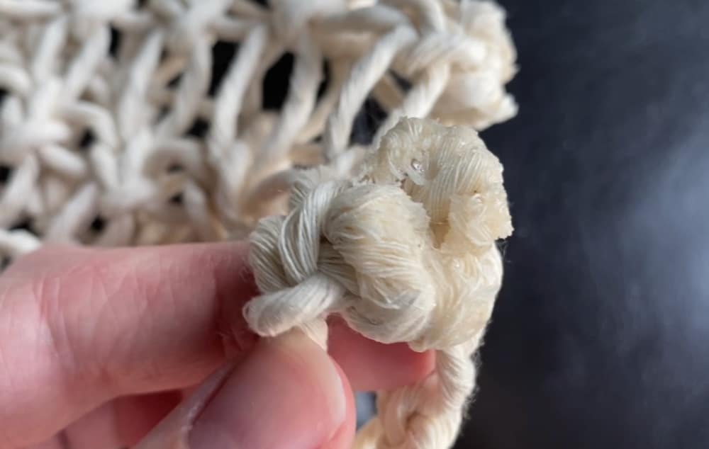 Ends glued down and pressed against the knot on DIY macrame bag